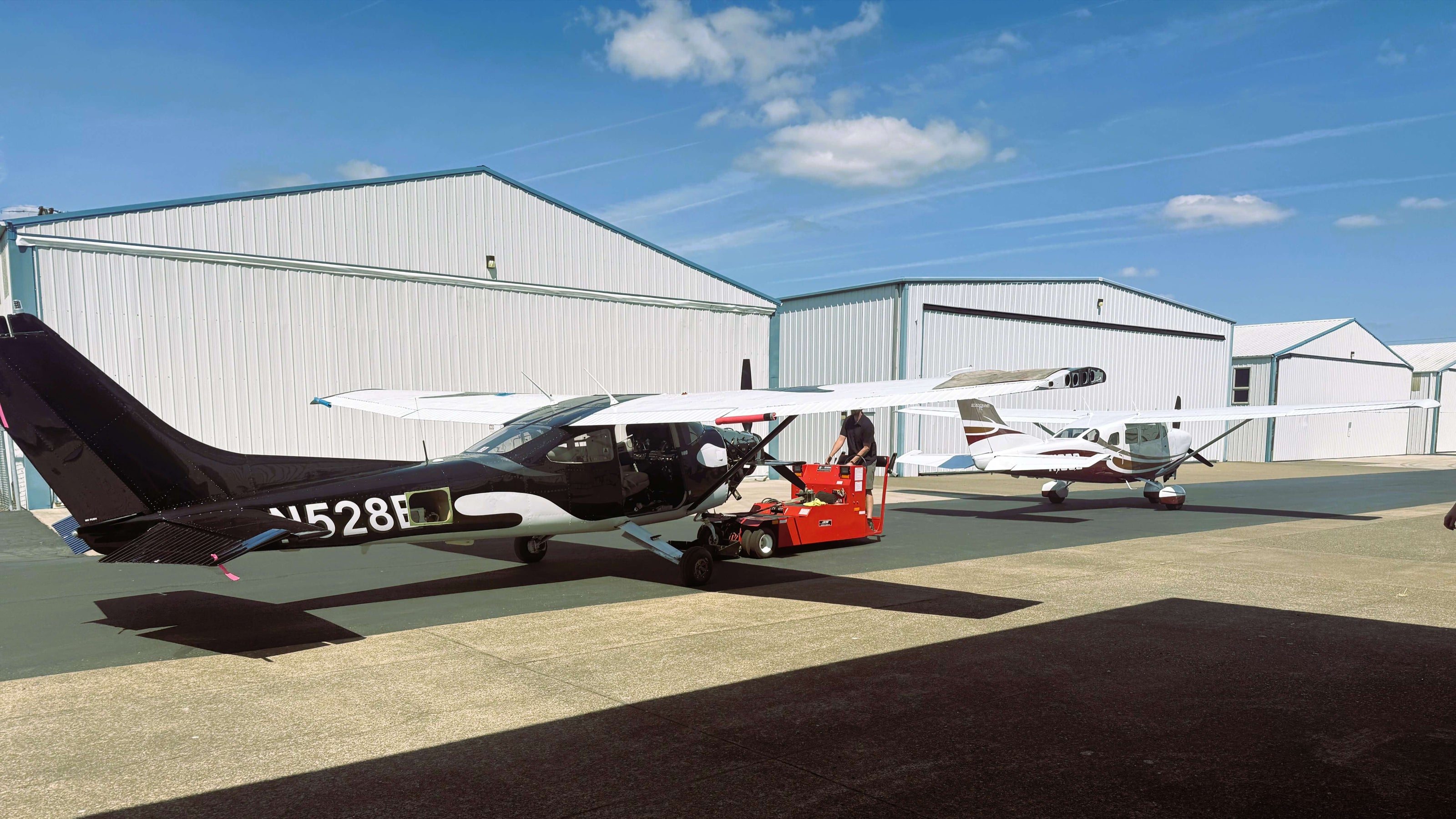 Cessna 182 & Cessna 206 Positioned for maintenance with hangars in background