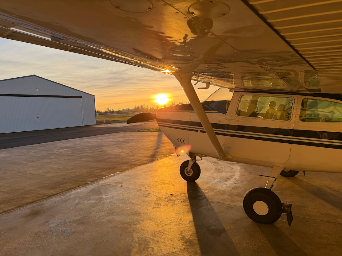 Cessna airplane in a hangar with a sunset in the background