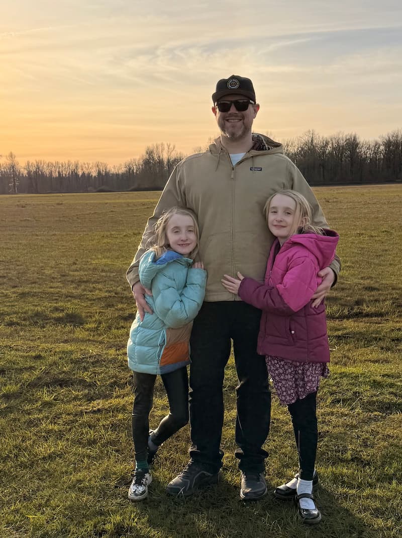 Aircraft Charter Broker standing with kids outside of Canby at the Molalla River Park with a forest in the background.