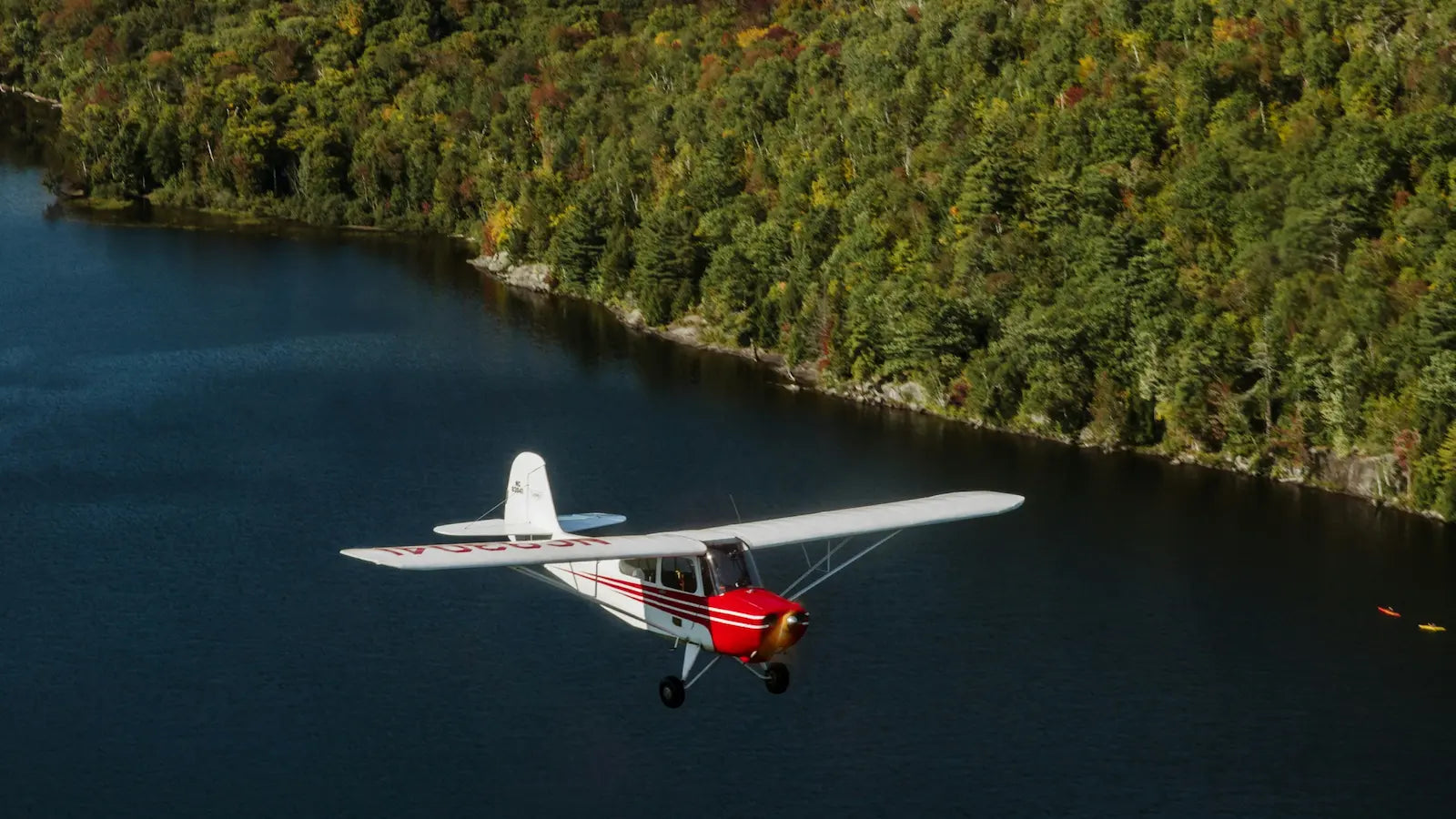 Small airplane flying over Pacific Northwest river with trees on the shore