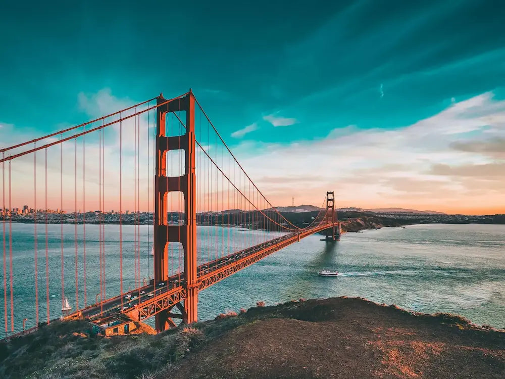 The Golden Gate Bridge going into San Fransico during sunset with a clear blue sky.