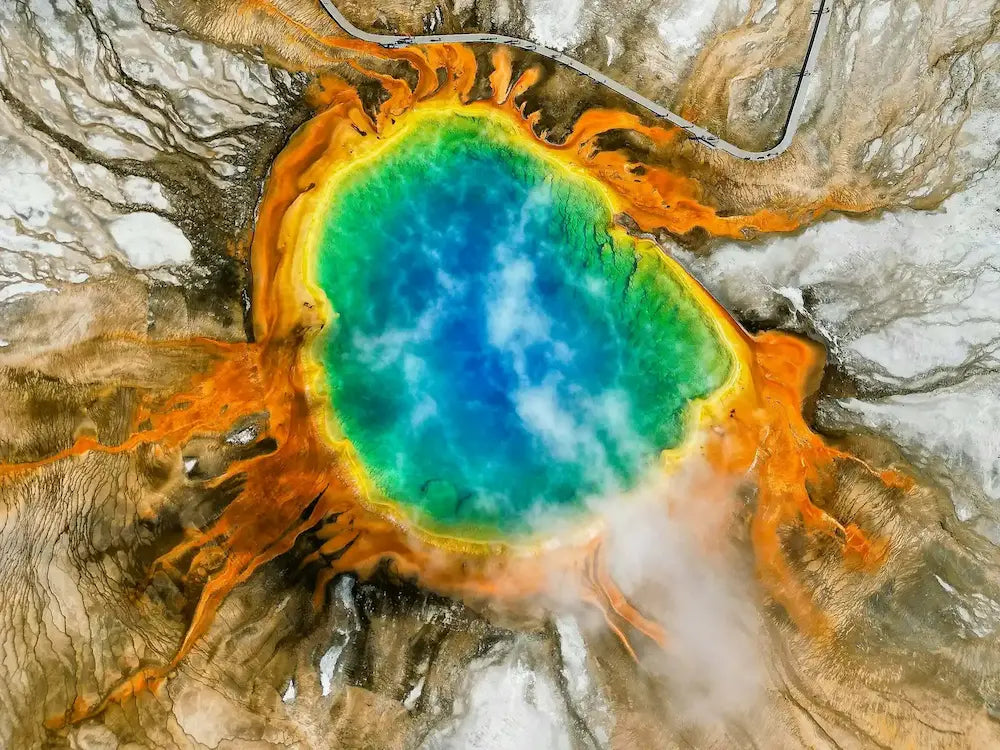 Colorful hot spring in Yellowstone with concentric circles of orange, yellow, and blue in a natural setting.