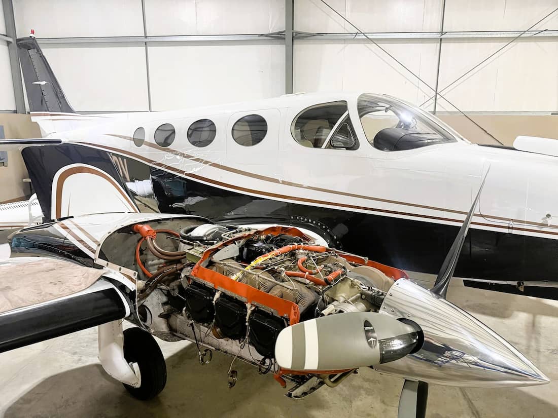 Twin engine Cessna with an engine exposed for maintenance