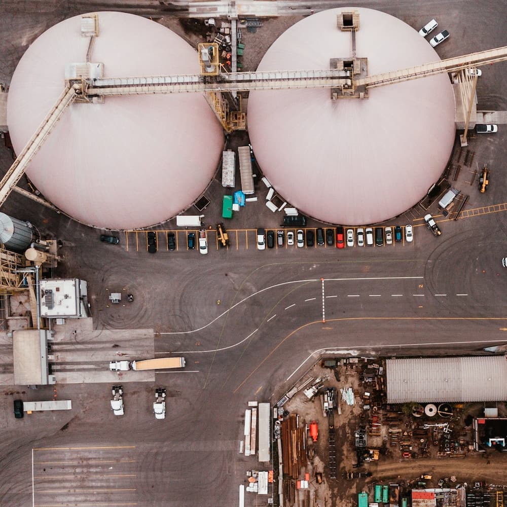 Aerial view of large industrial facilities, likely for storage or manufacturing, with several vehicles and industrial structures visible.