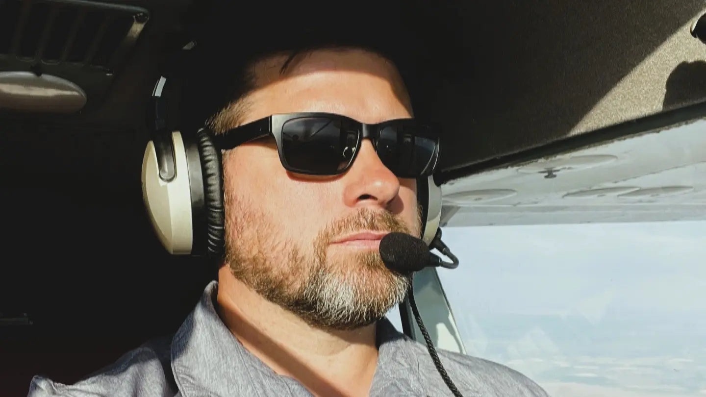 Pilot wearing sunglasses and a headset inside an airplane cockpit