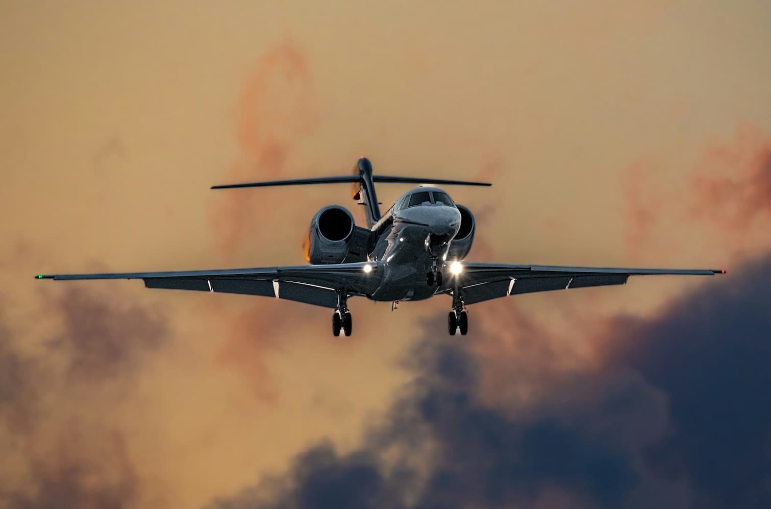 Private jet flying against a dramatic sky with orange and purple hues